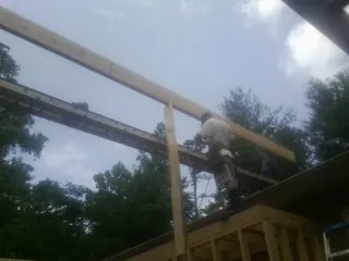Carpenter setting a ridge beam over a new addition frame — Ice Dam Removal by Roofing Brothers in Francis Creek