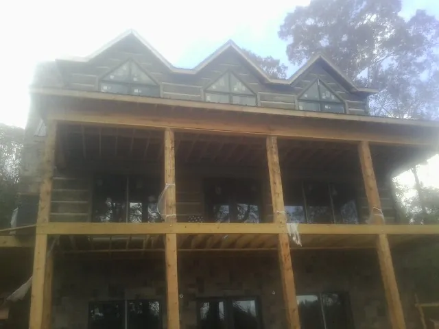 Dormers and porch framing on a large log home under construction — Roof Coating work by our crew in Francis Creek