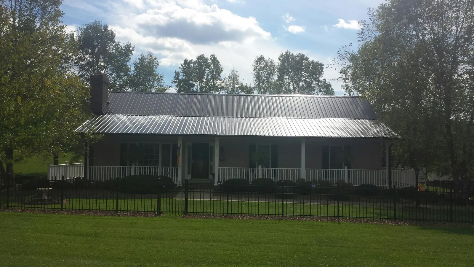 Gray metal roof on a brick ranch with a full width front porch — Gutter Guard Installation work by our crew in Francis Creek