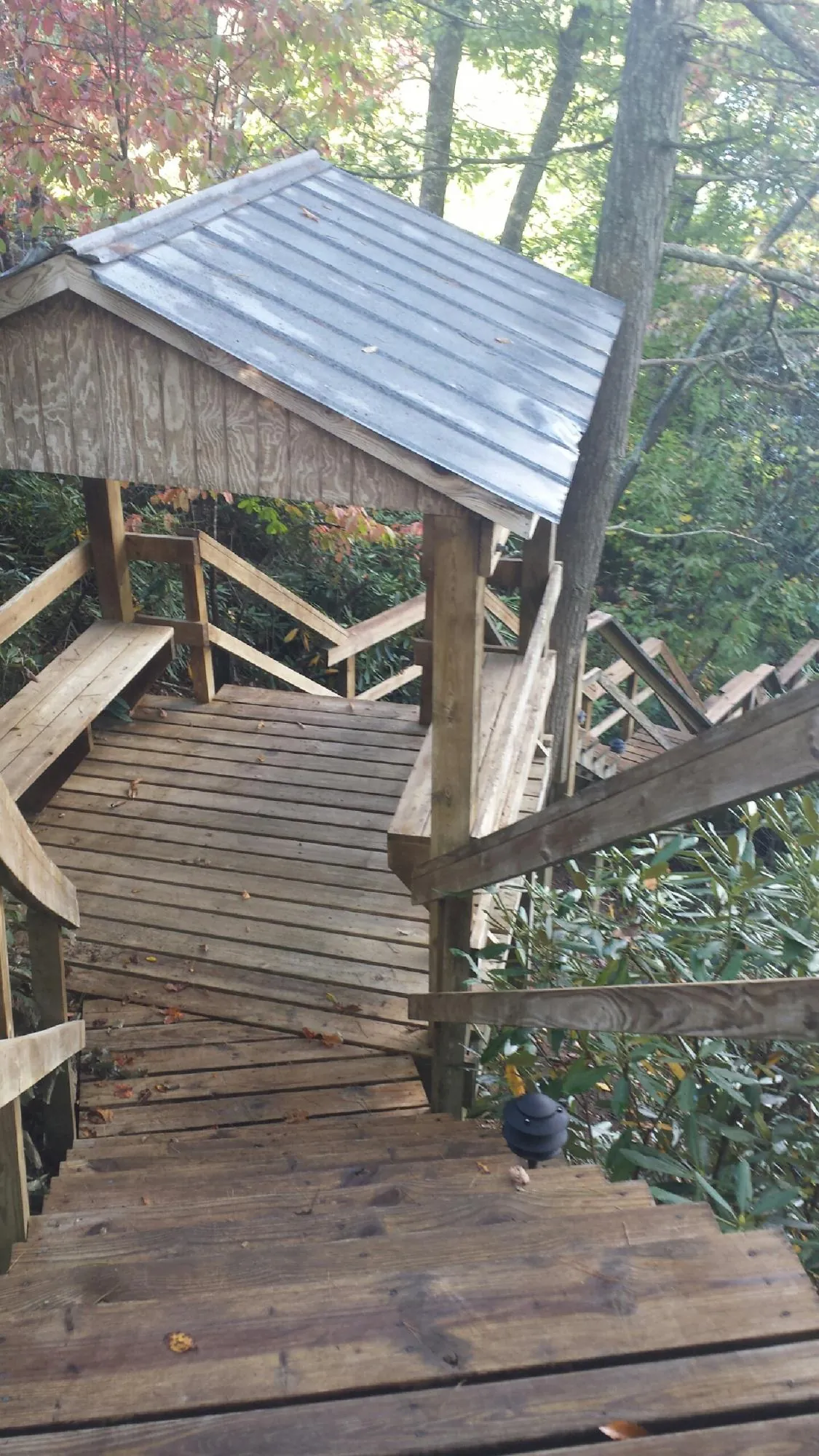 Metal roofed shelter over wooden steps on a wooded walkway — Skylight Repair & Installation work by our crew in Francis Creek