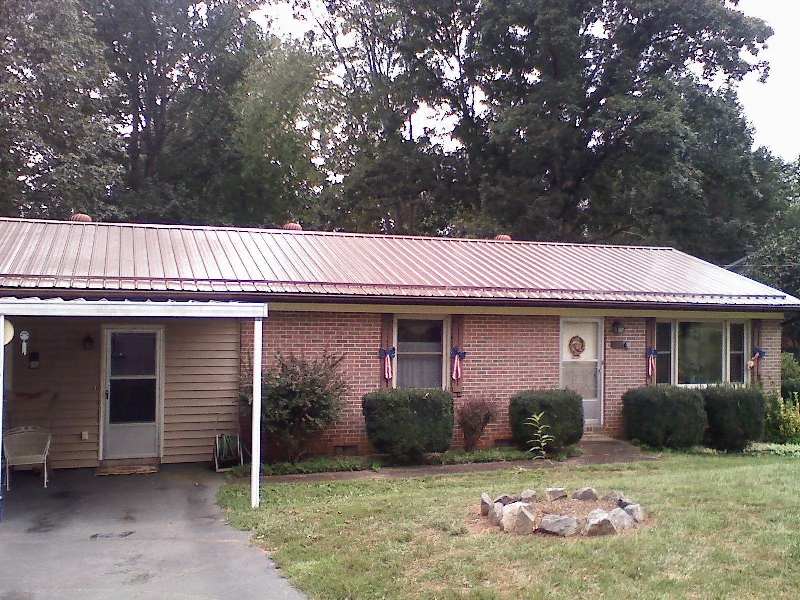 Bronze metal roof and carport on a brick ranch home — Roof Repair work by our crew in Francis Creek