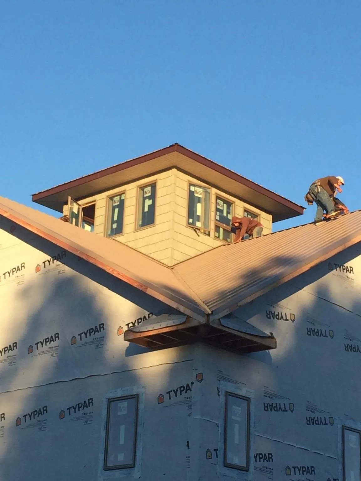 Roofers working around a rooftop cupola on a new metal roof at sunset — Roof Waterproofing in Francis Creek by Roofing Brothers